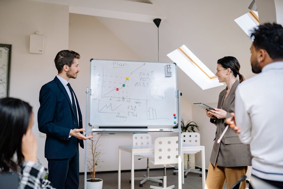 Colleagues collaborating at a business meeting, analyzing graphs on a whiteboard.