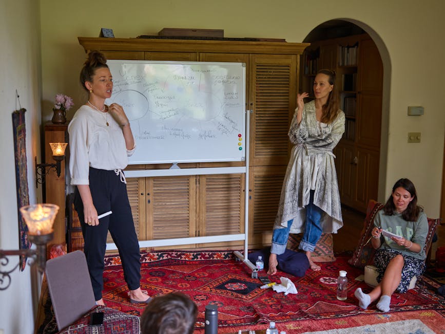 A group of adults in a cozy room participating in a casual meeting with a whiteboard.